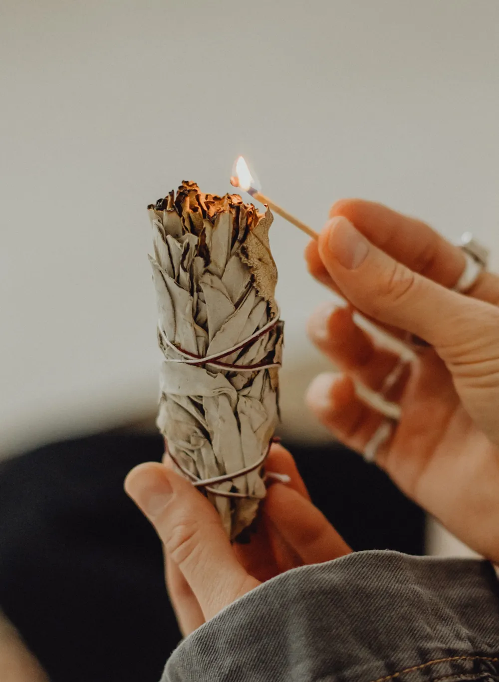 Eine Frau hält einen kleinen weißen Smudge Stick, perfekt für Kundalini Yoga und Coaching zur Förderung von Wohlbefinden.